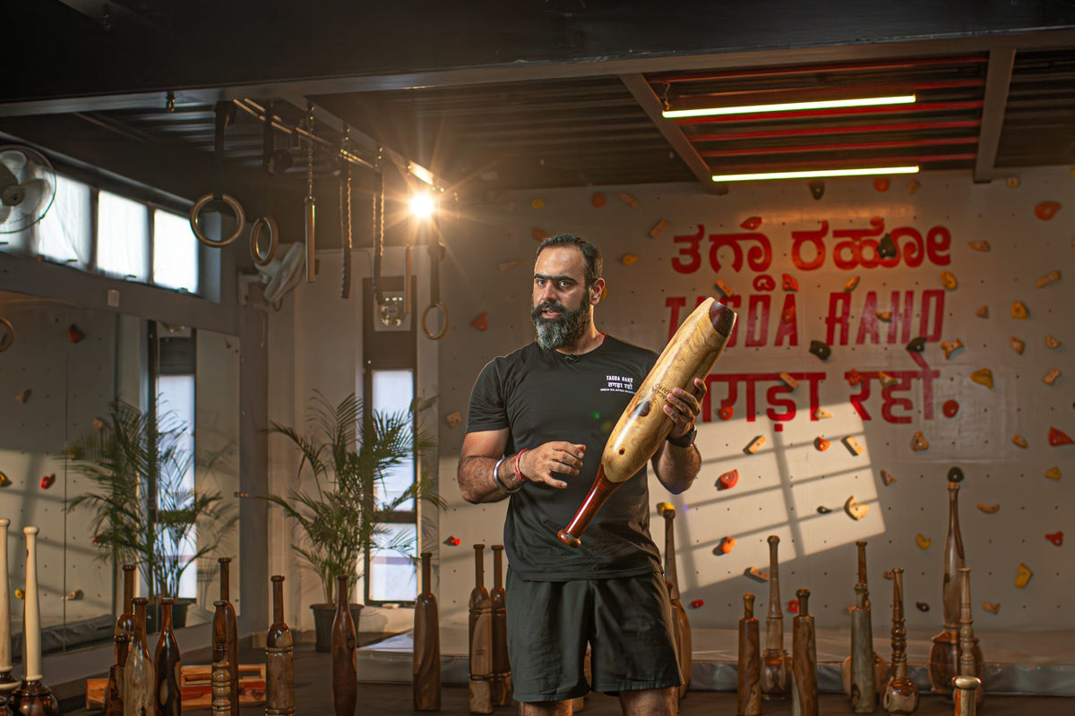 A Tagda Raho coach holding a Mudgar in the training hall